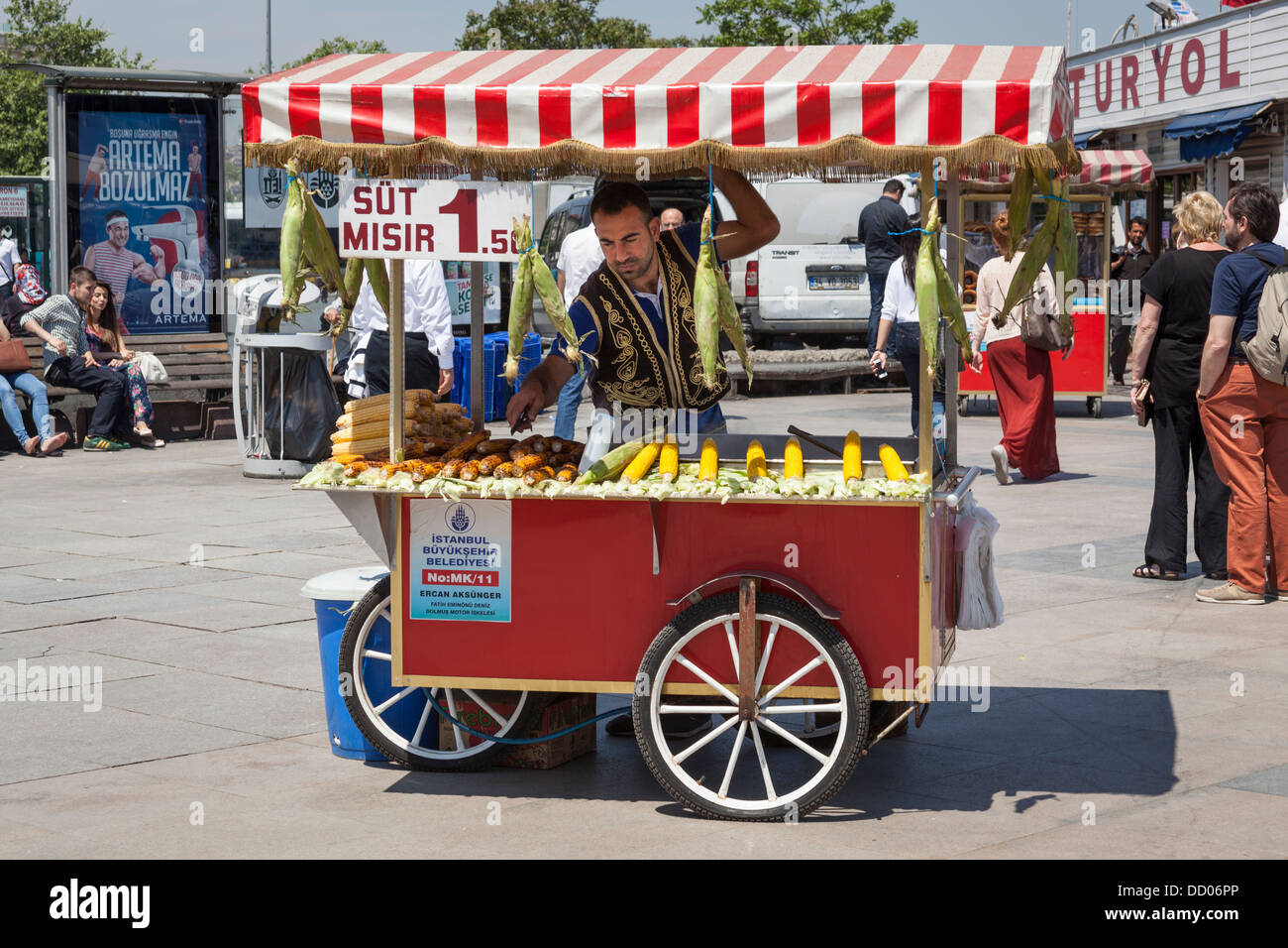 L'uomo vendere sulla pannocchia di mais da un mobile di stallo alimentare, Eminonu, Golden Horn, Istanbul, Turchia Foto Stock