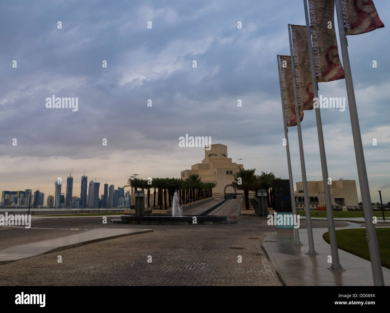 Fontana e un lungo viale alberato passeggiata fino al museo di arte islamica con lo skyline della città sullo sfondo a Doha, in Qatar, medio oriente Foto Stock