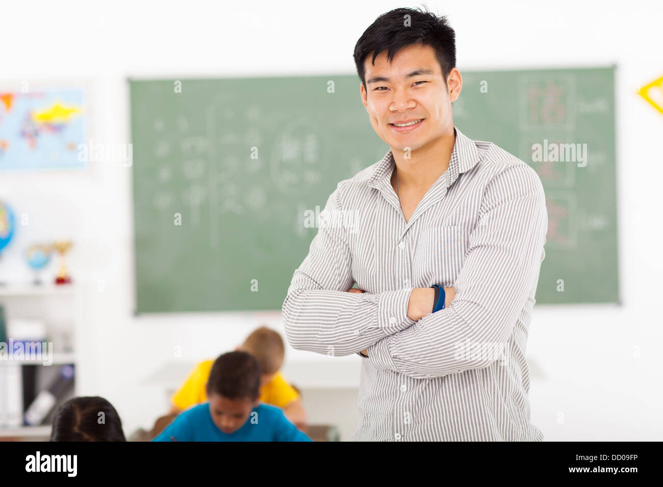 Felice asiatico maschio insegnante di scuola elementare in aula Foto Stock