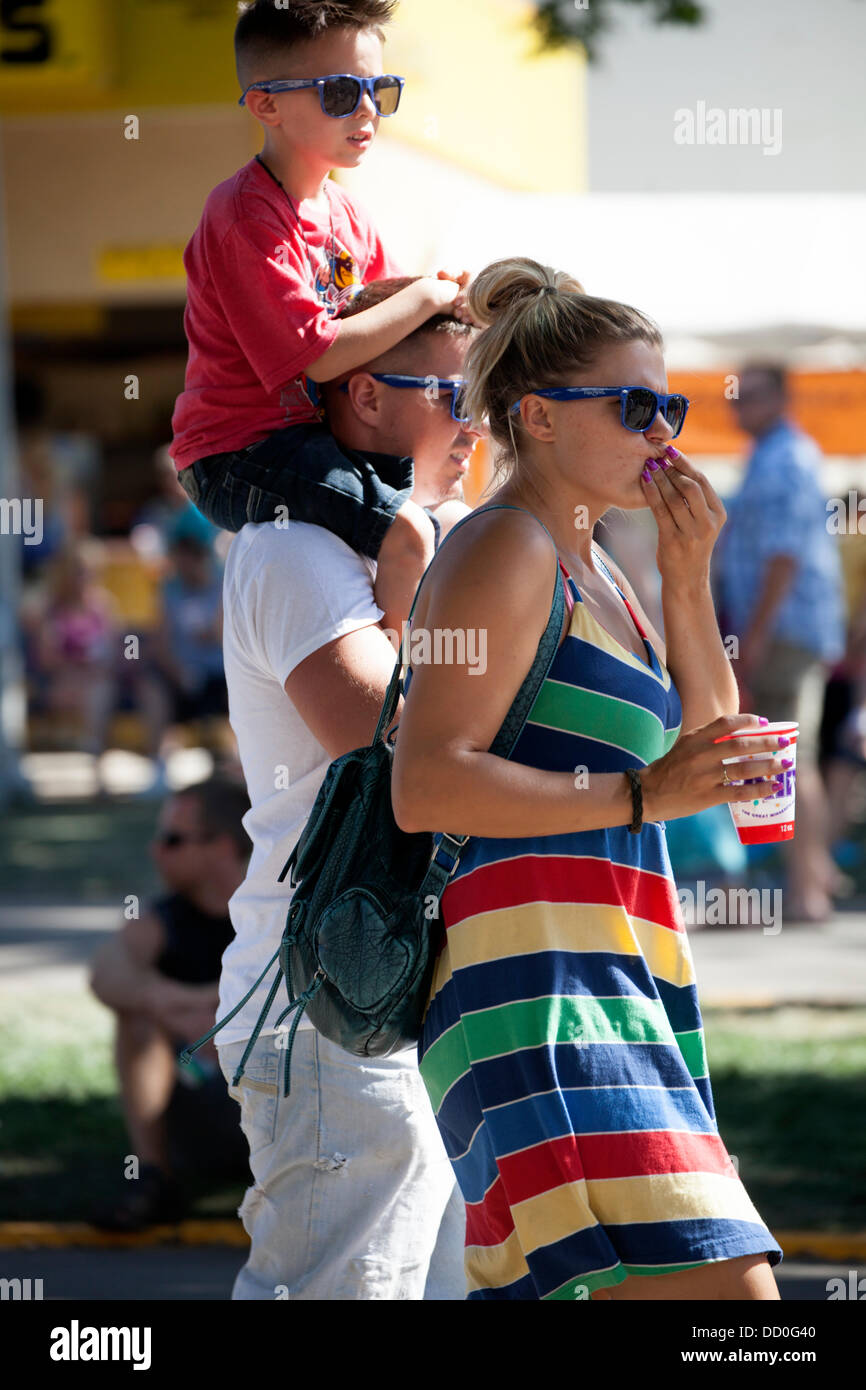 Famiglia indossando occhiali da sole cool a piedi attraverso la fiera con figlio a cavallo di papà alle spalle. Minnesota State Fair il giorno di apertura giovedì 22 agosto 2013 St Paul Minnesota MN USA Foto Stock