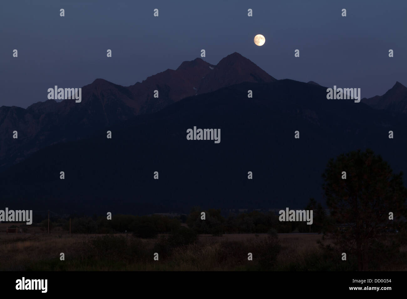 La luna piena sorge sopra le montagne di missione in Montana, USA. Preso da Ninepipe National Wildlife Refuge. Foto Stock