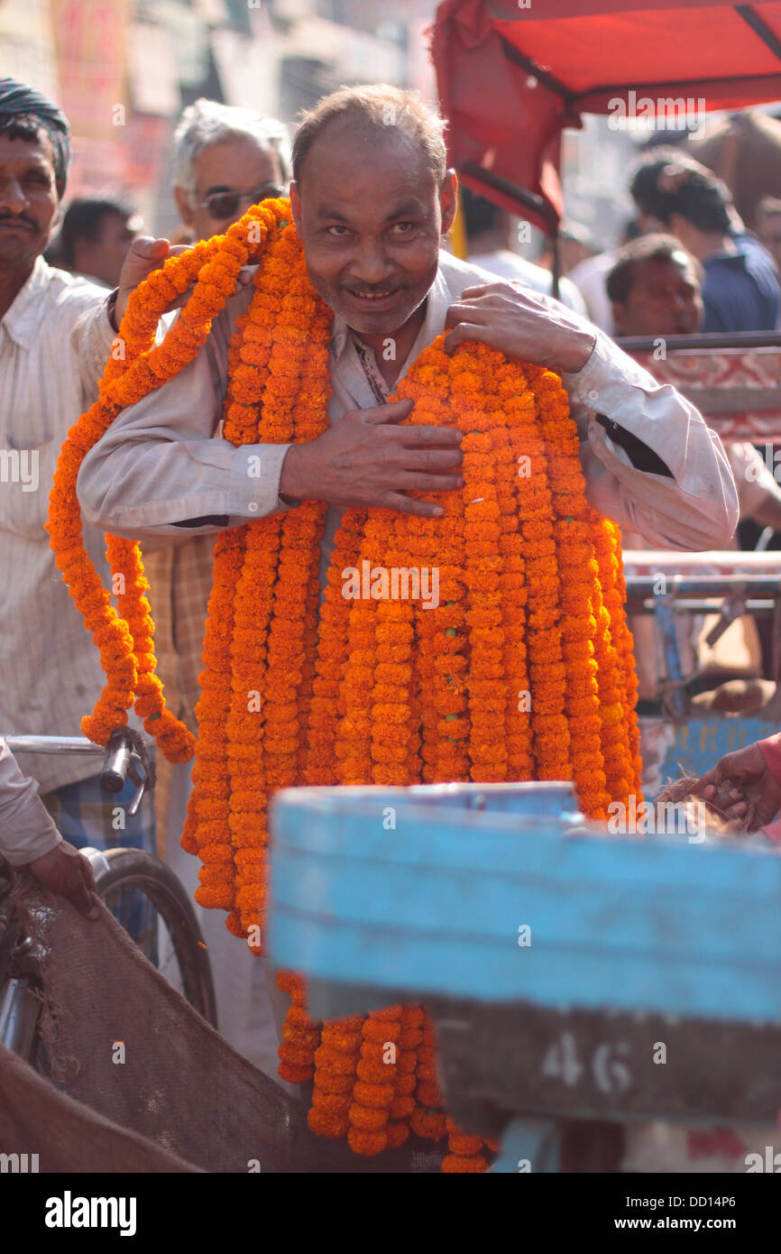 Un venditore di fiori di tagete porta ghirlande intorno al suo collo al Chandni Chowk mercato dei fiori nella Vecchia Delhi, India. Foto Stock