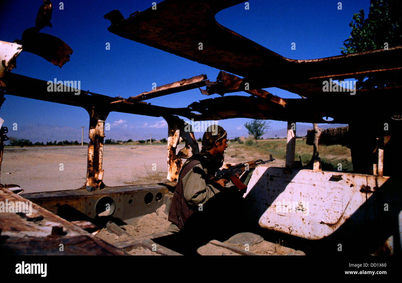 Fighter dell' Alleanza del Nord le protezioni la strada da Jabol Seraj o Jabal Saraj a Charikar durante la guerra con i Talebani. Egli prende la copertura in un distrutto costruite dai sovietici come trasporto di personale APC. Foto Stock