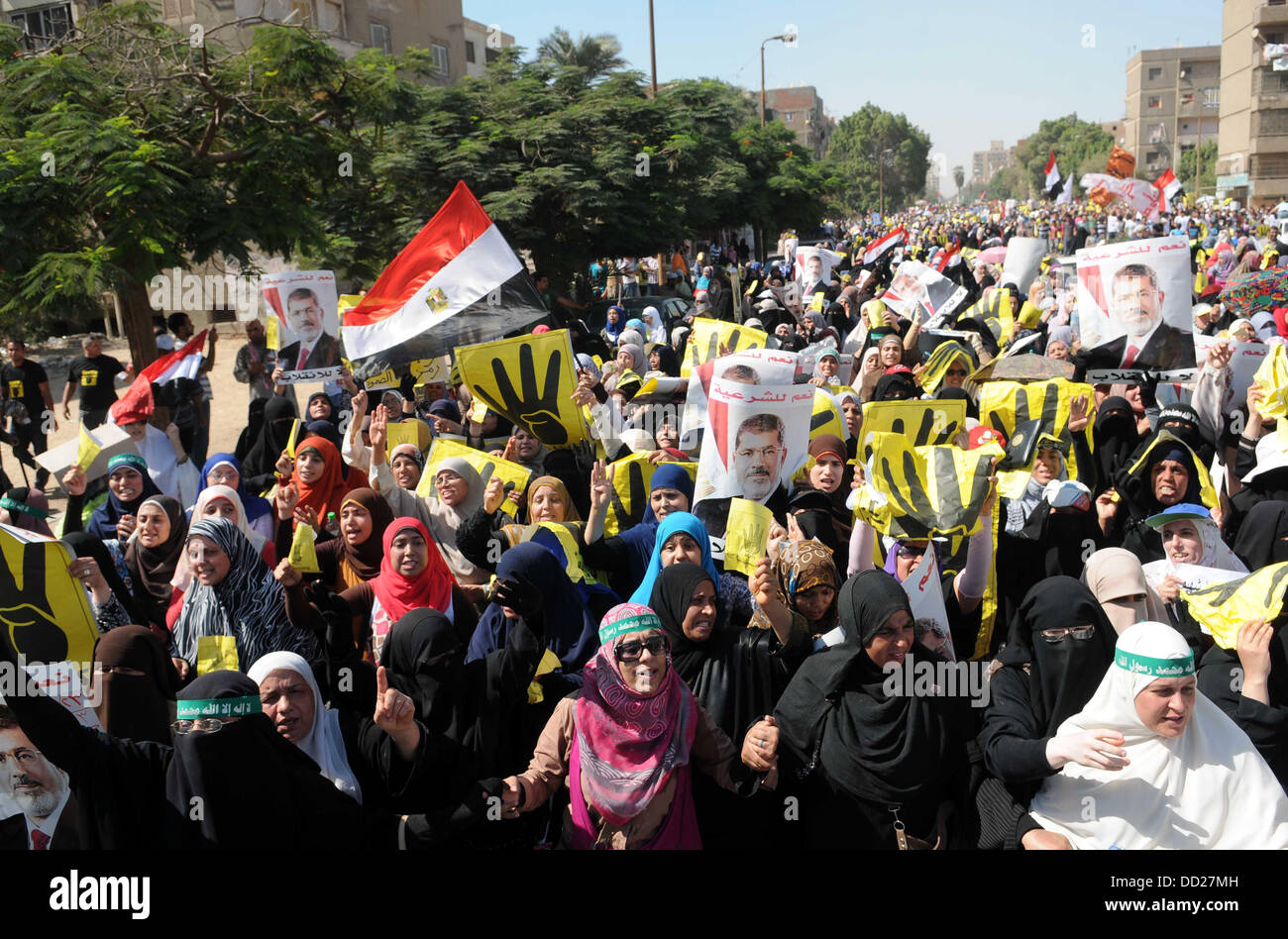 Il Cairo, il Cairo, Egitto. 23 Ago, 2013. Gli egiziani i sostenitori del deposto presidente Morsi tenere manifesti raffiguranti lui e gli altri che raffigura una mano in un segno di numero quattro durante un venerdì di protesta per la chiamata dalla Fratellanza Musulmana in Helwan, Egitto, 23 agosto 2013. I quattro è un riferimento alla moschea vicino al più grande il sit-in posizione denominata Rabaa Al-Adawiya, Rabaa essendo il nome di un Santo ma ha anche il significato di "quattro" in arabo. Foto Stock