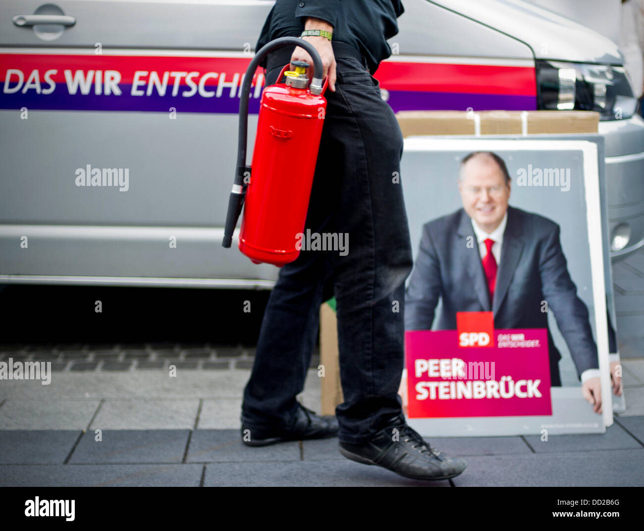 Un dipendente della tedesca il Partito socialdemocratico (SPD) detiene un estintore come egli va al di là di un cartellone elettorale che mostra il Cancelliere SPD candidato Peer Steinbrueck in Langenfeld, Germania, 23 agosto 2013. Foto: JAN-PHILIPP STROBEL Foto Stock