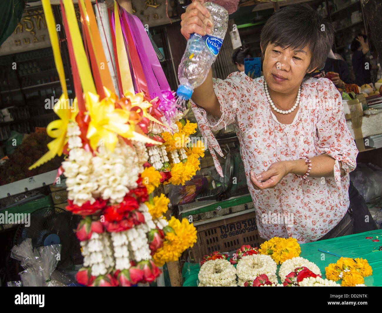 Agosto 23, 2013 - Bangkok, Tailandia - un fornitore acque ghirlande di fiori ella è la vendita in Pak Khlong Talad, il mercato dei fiori in Bangkok. La Thailandia è entrato un Ã¢??technicalÃ¢?Â recessione questo mese dopo l'economia si è ridotto di 0,3% nel secondo trimestre di quest'anno. Il 0,3% la contrazione del prodotto interno lordo tra aprile e giugno a seguito di una caduta precedente del 1,7% durante il primo trimestre del 2013. La contrazione è imputabile a un calo della domanda di esportazioni, una caduta della domanda interna e una perdita di fiducia dei consumatori. Allo stesso tempo il valore del baht tailandese contro il dollaro USA ha dropp Foto Stock