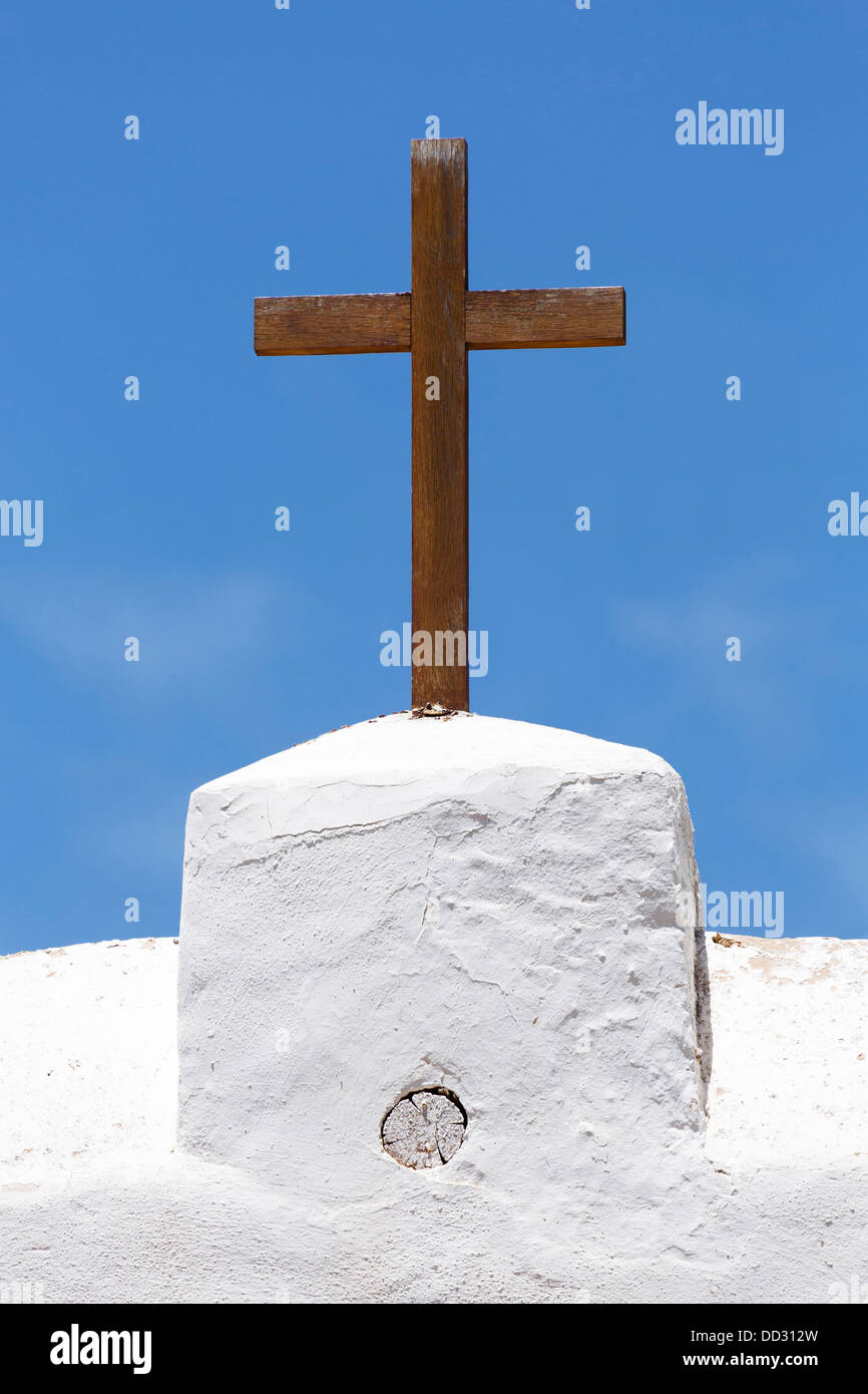 Una croce cristiana di legno su una chiesa bianca contro un cielo blu Foto Stock