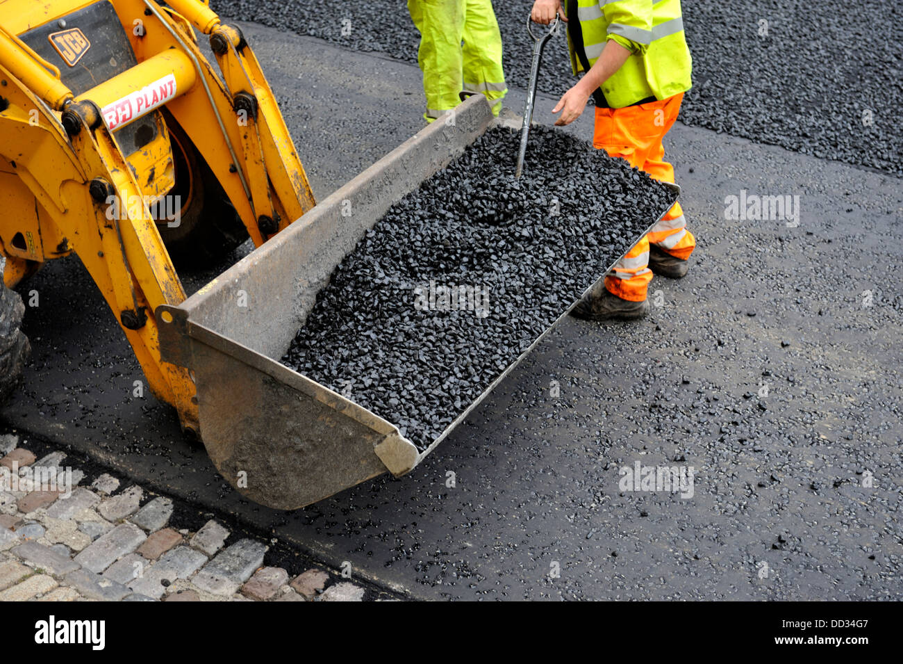 Workman diffusione di asfalto durante il rifacimento della pavimentazione stradale e la riparazione Foto Stock