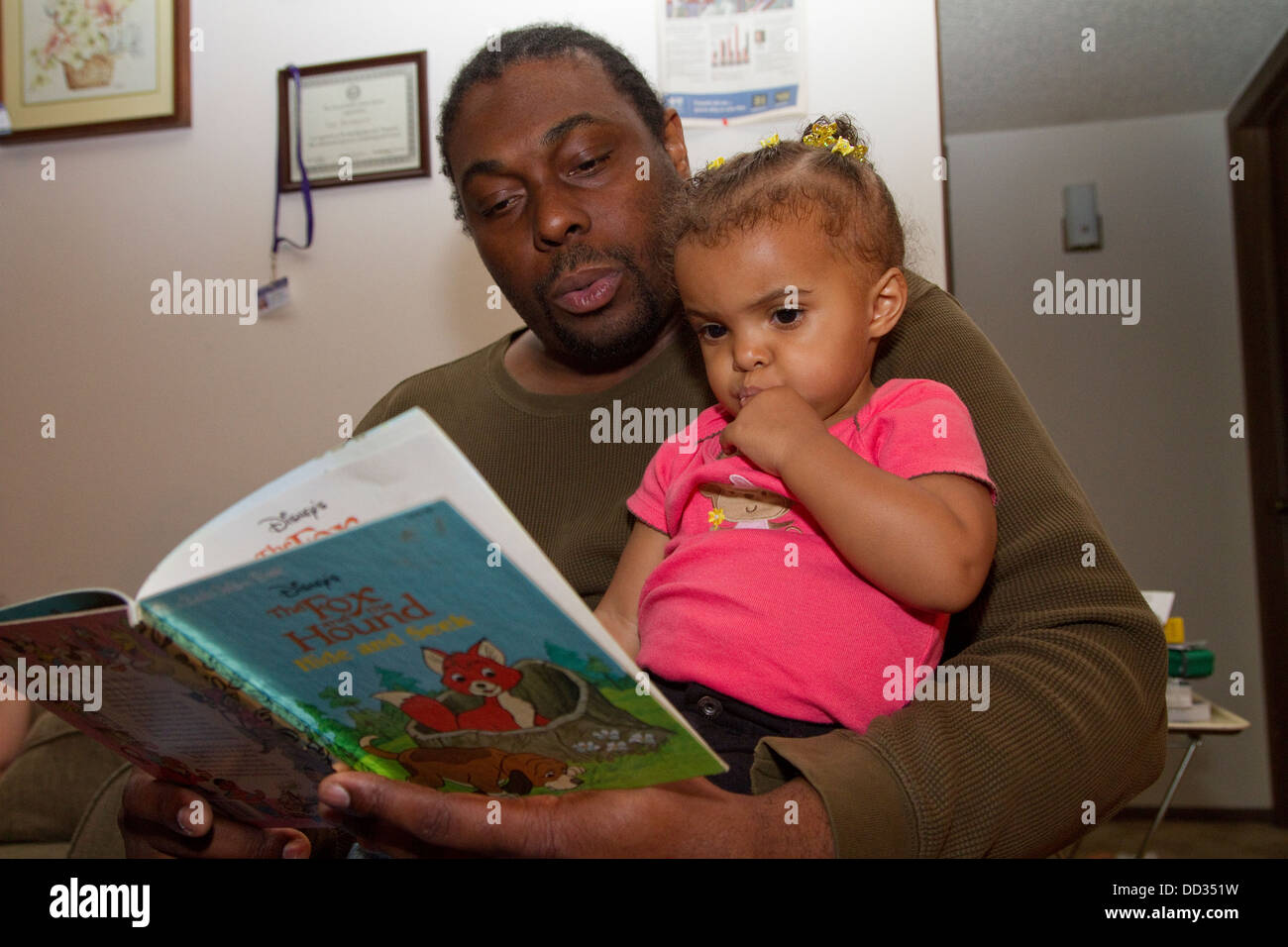 Maschio afro-americano ex detenuto la lettura alla sua giovane figlia. Questo detenuto è riuscito a ottenere un grado dopo il suo rilascio. Foto Stock
