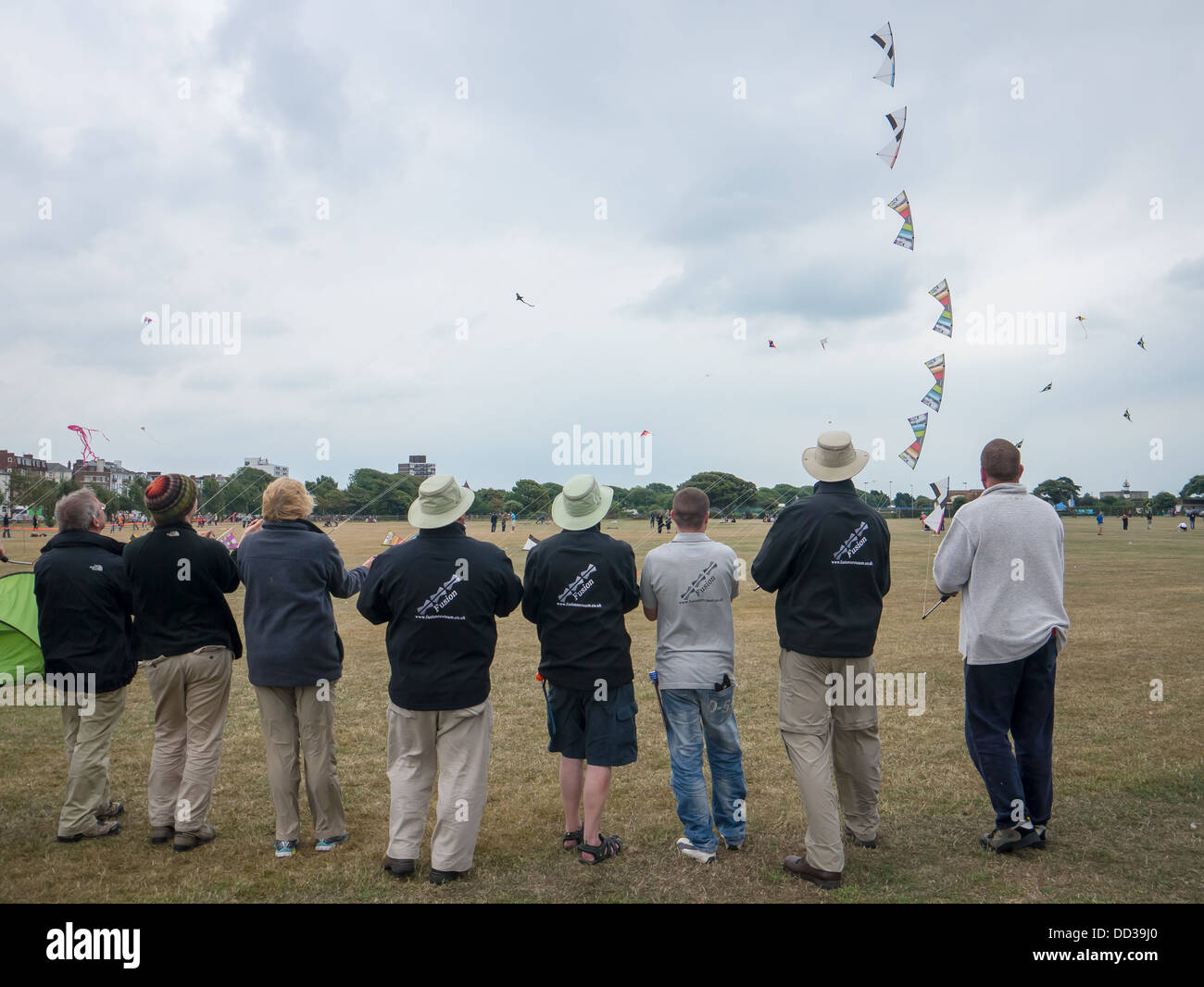 I membri di un kite team display stand in linea e volare i loro aquiloni nel coordinamento. Foto Stock