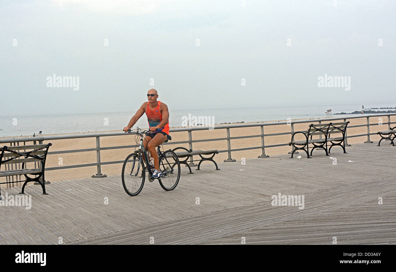 Un uomo esercita sulla sua bicicletta sul Biegelman Boardwalk in Spiaggia di Brighton Brooklyn, New York. Foto Stock