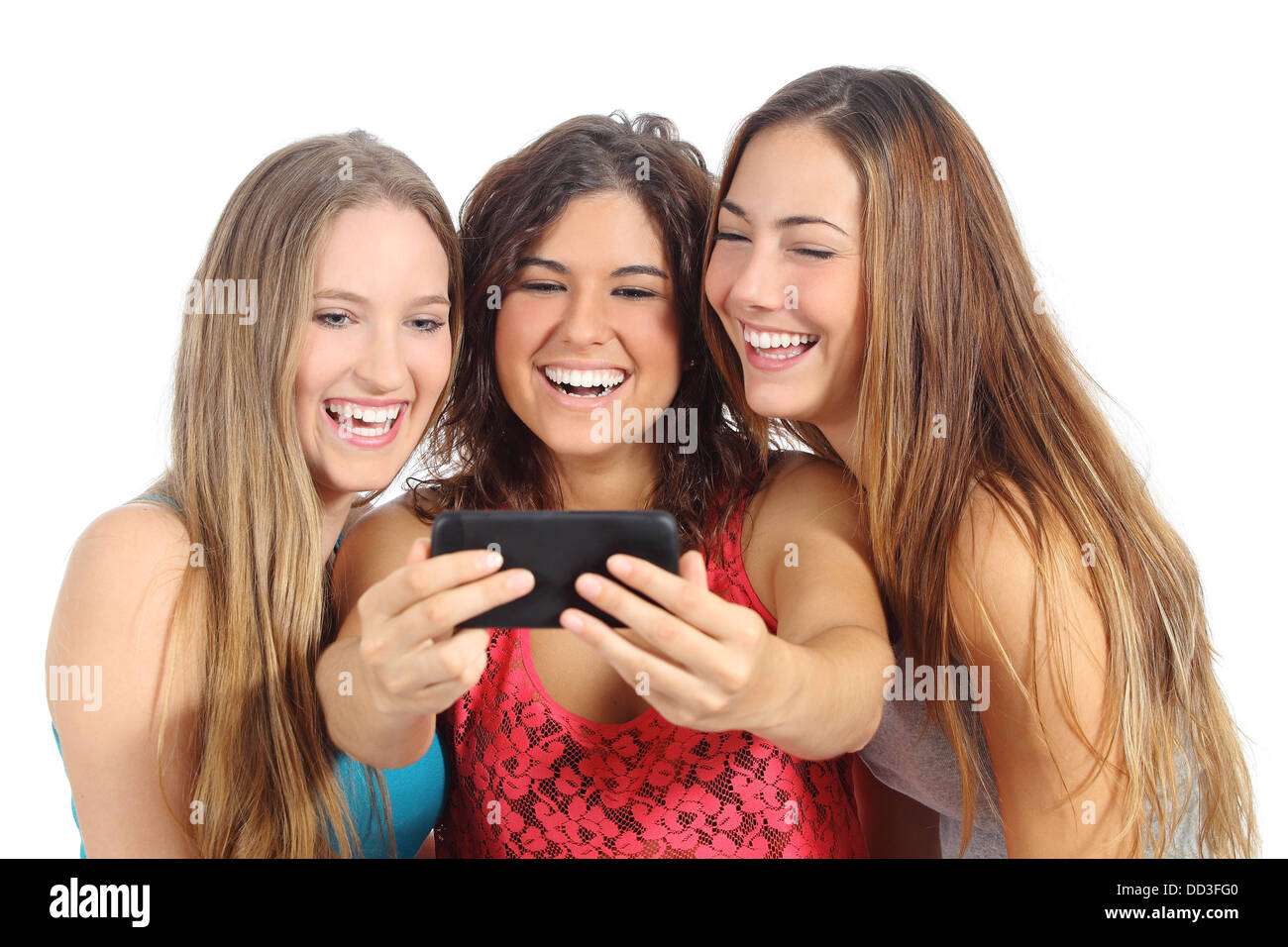 Un gruppo di tre ragazze teenager di ridere guardando la smart phone isolato su uno sfondo bianco Foto Stock