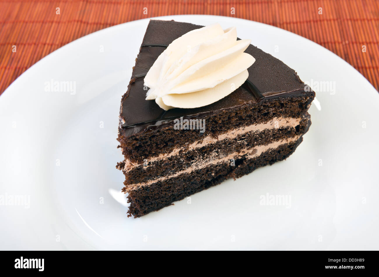 Pezzo di torta al cioccolato sulla piastra bianca a tavola Foto Stock