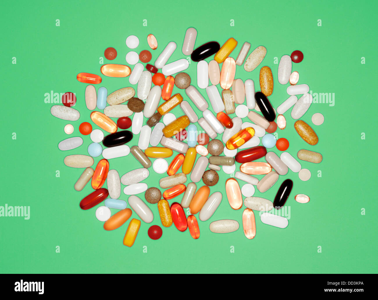 Una collezione di sfusi di varie pillole, compresse e capsule su uno sfondo verde Foto Stock