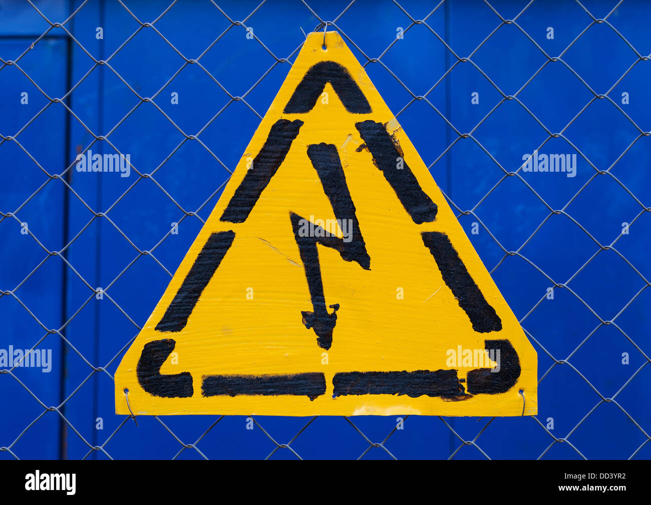 Alta tensione segno giallo montato su blu metallo griglia rabitz Foto Stock