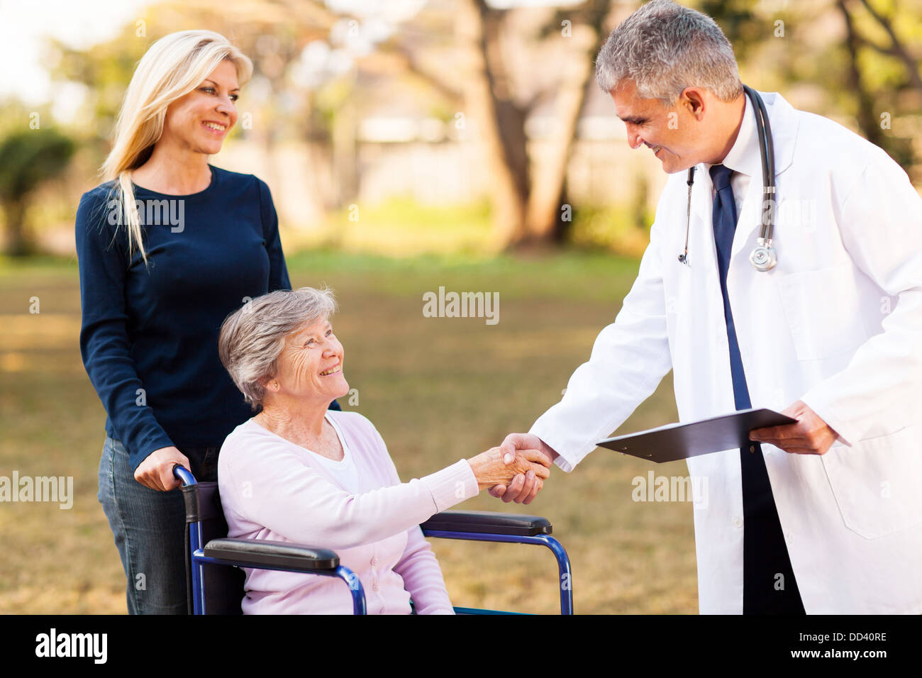 Amichevole maschio handshaking medico con il paziente senior all'aperto Foto Stock