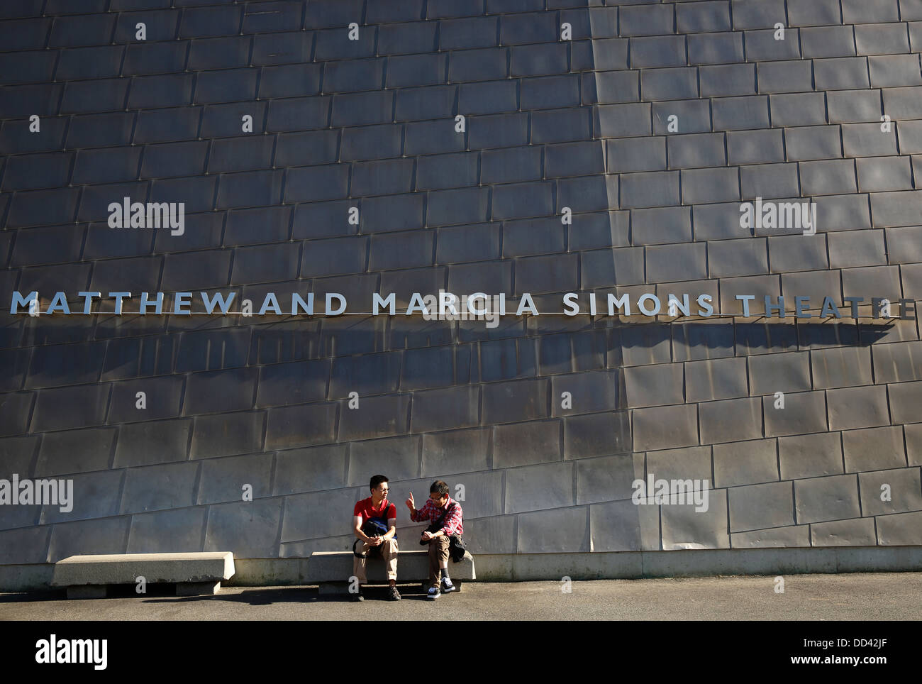 Due uomini seduti su una panchina di fronte al teatro IMAX al New England Aquarium di Boston, Massachusetts Foto Stock