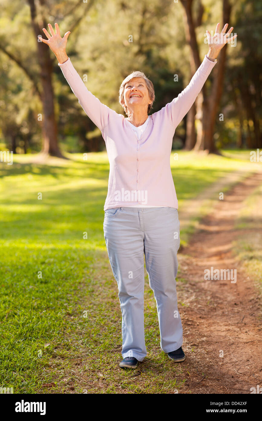 Un sano stile di vita di pensionamento concetto: happy senior donna con braccia tese all'aperto Foto Stock
