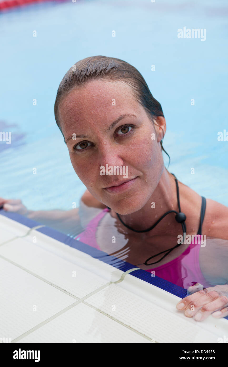 Nuotatore femmina in appoggio sul bordo della piscina esterna Foto Stock