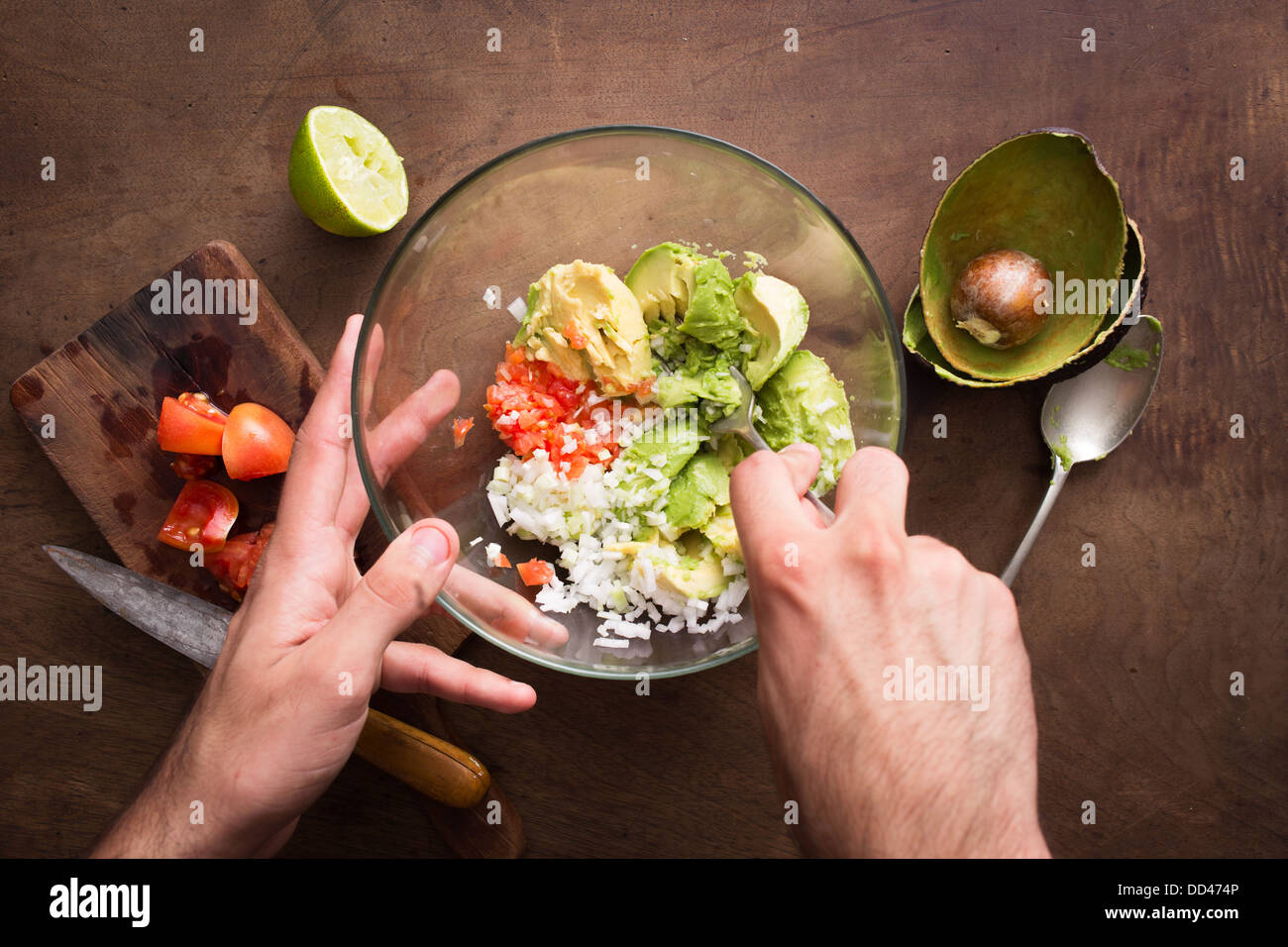 Schiacciare le verdure per fare il guacamole sul tavolo in legno si affacciano Foto Stock