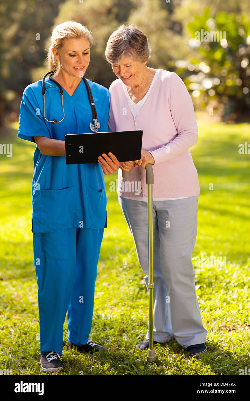Sorride mostrando infermiere paziente senior il suo medico i risultati di prova all'aperto Foto Stock