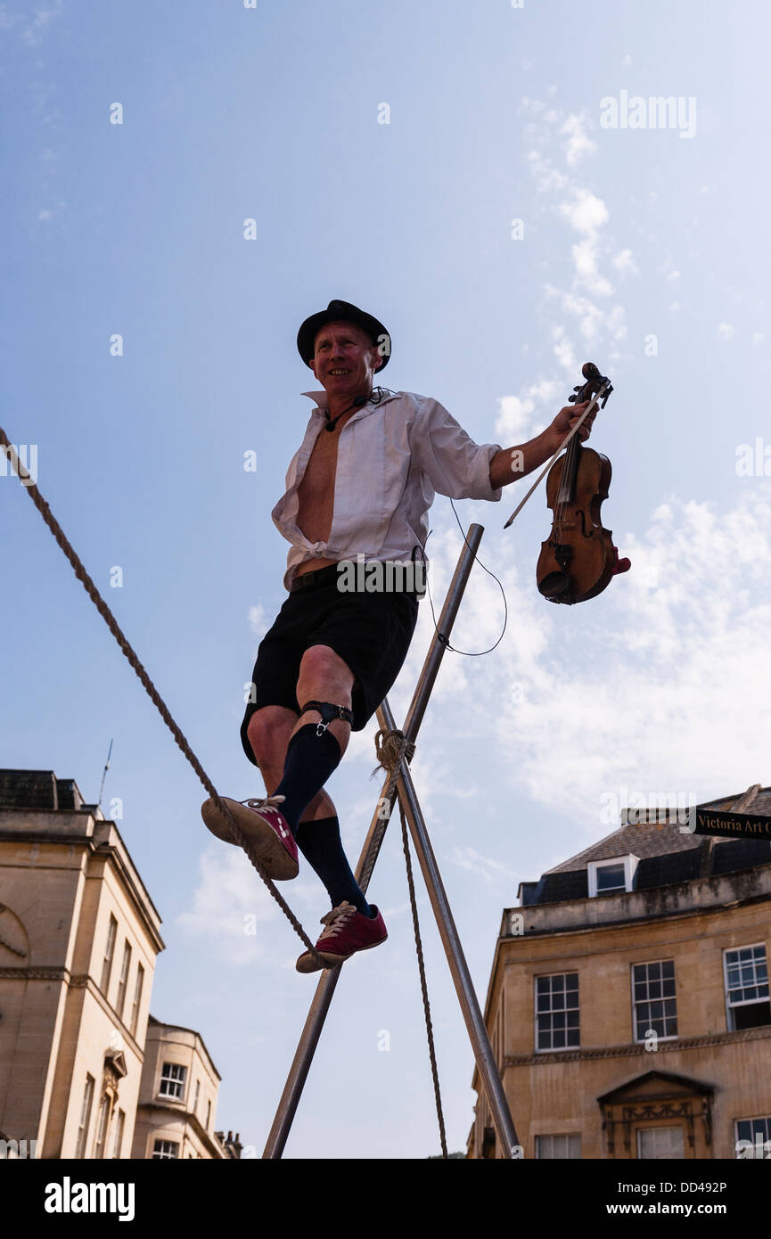 Un funambolo musicista di strada la riproduzione di un violino in bagno , Somerset , Inghilterra , Inghilterra , Regno Unito Foto Stock