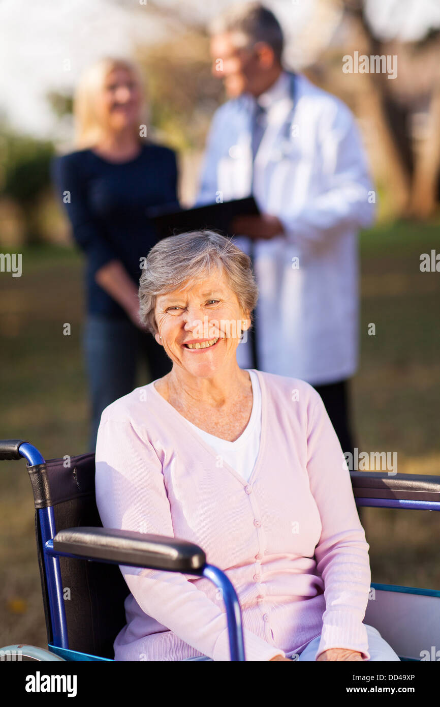 Sorridente disabili donna senior all aperto con la figlia e il medico su sfondo Foto Stock