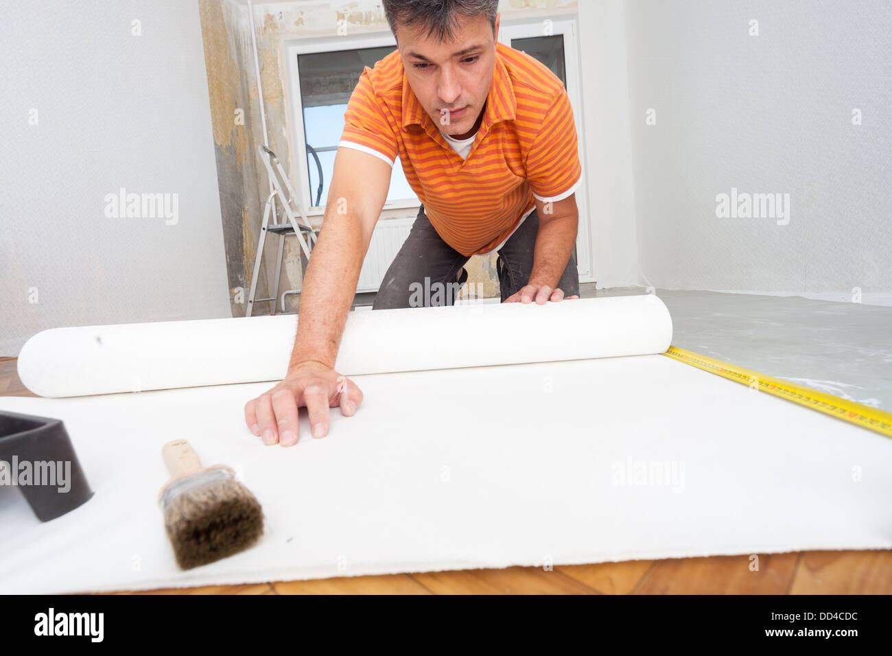 Riparazioni nell'appartamento. L'uomo colle carta da parati in camera. Foto Stock