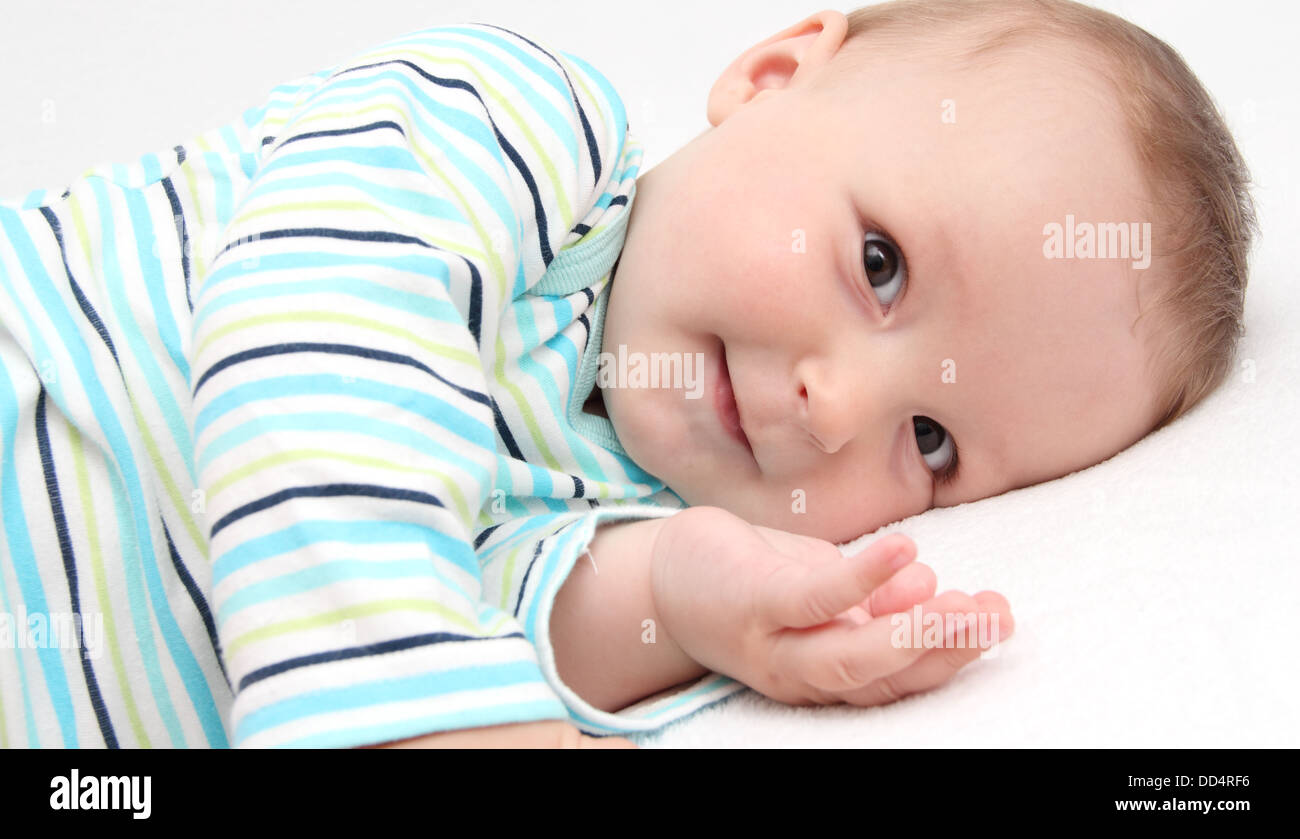 Piccolo Bambino giacente sul letto e guardare la fotocamera Foto Stock