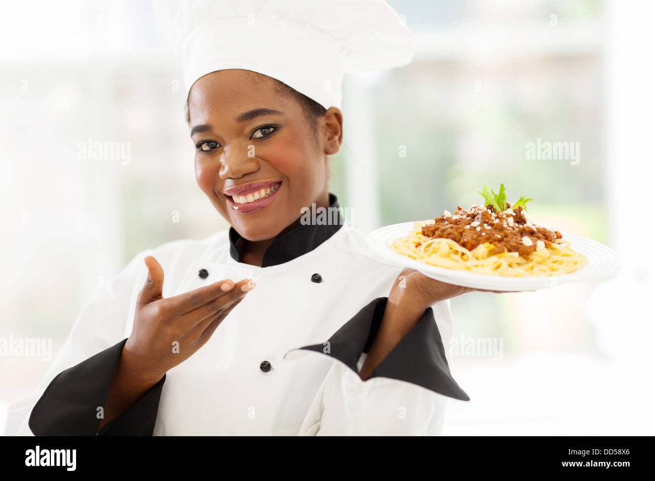 Bella Afro American chef presentando spaghetti Foto Stock