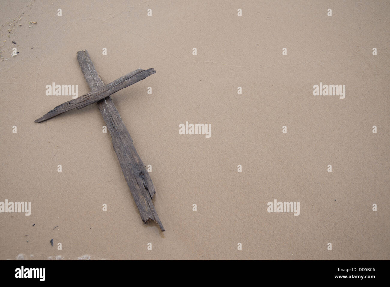 Una croce fatta di driftwood recante su di sabbia su una spiaggia. Foto Stock