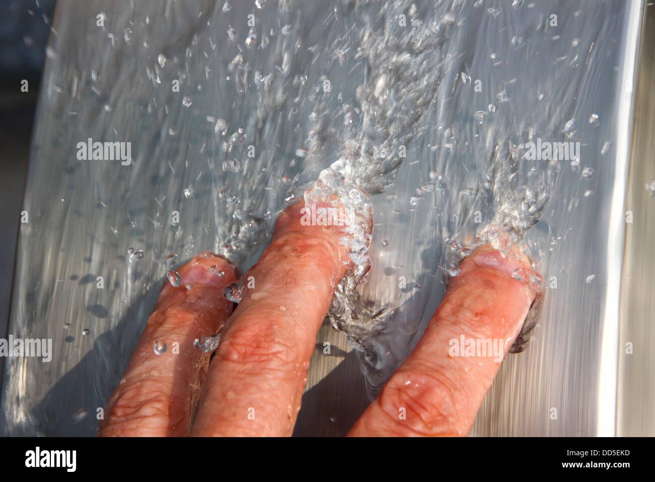 L'uomo le dita in acqua corrente Foto Stock