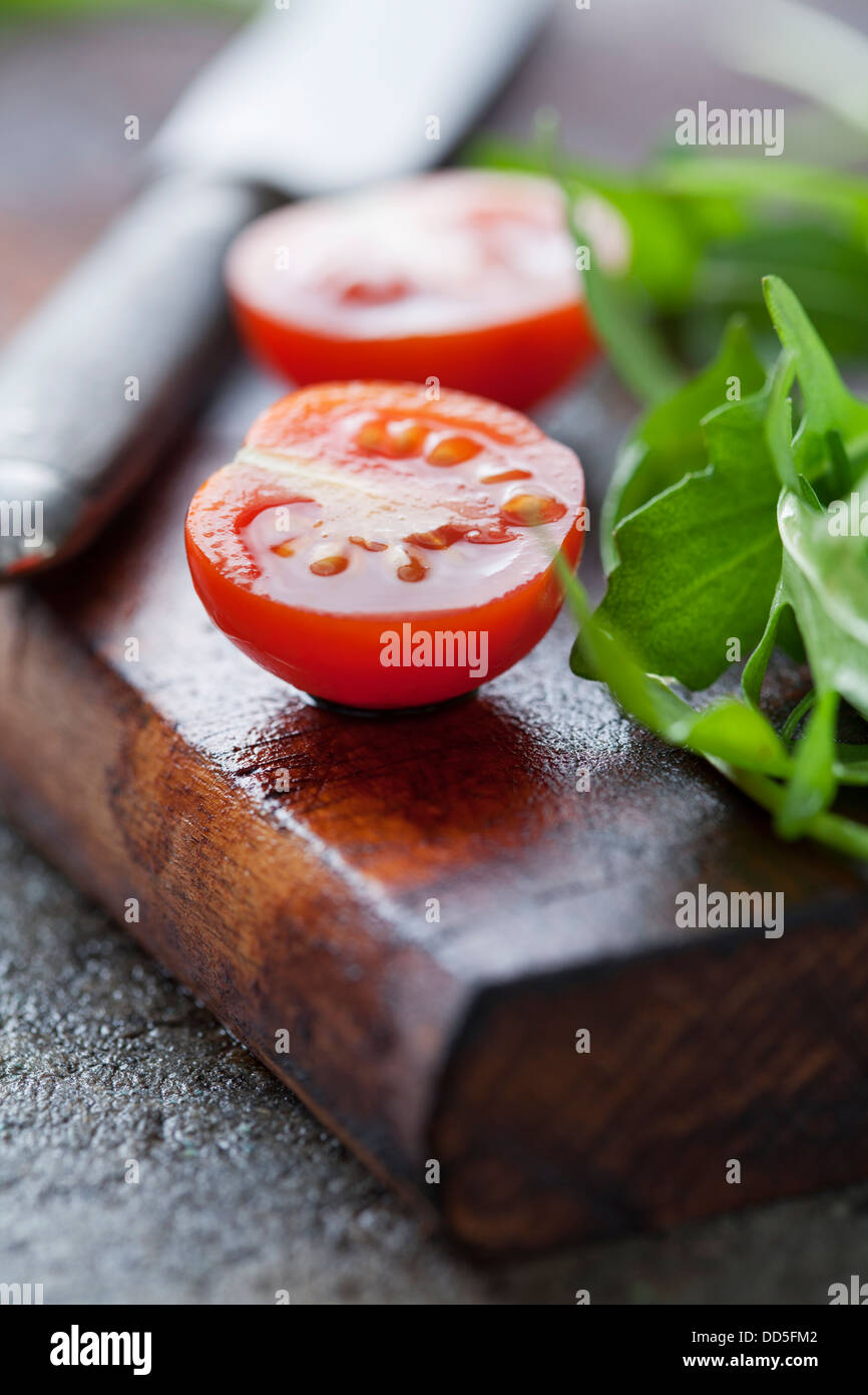 Rucola fresca e pomodori su un tagliere di legno Foto Stock