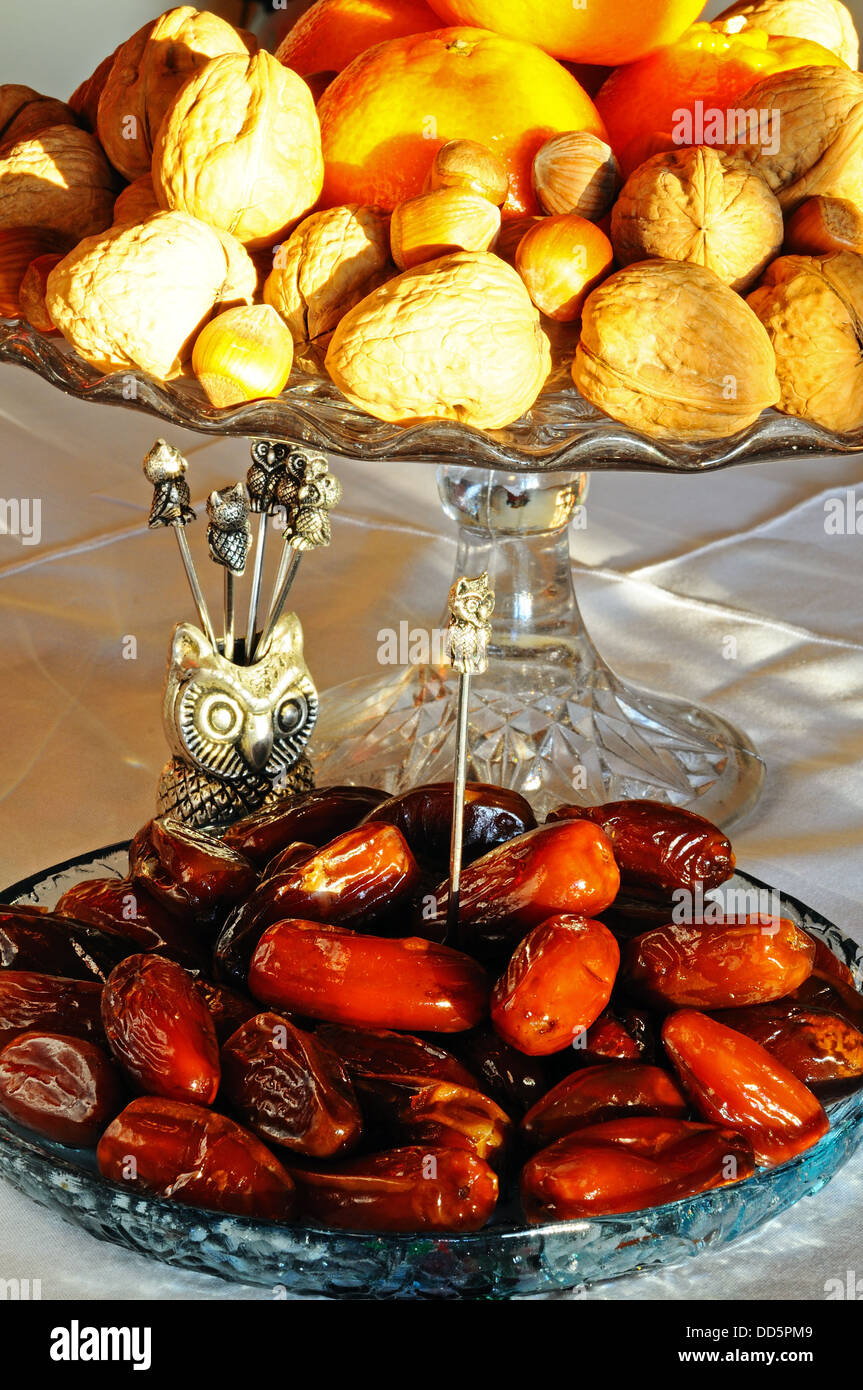 Date in un piatto di vetro basso con le noci, le nocciole e i satsuma per la parte posteriore, Inghilterra, Regno Unito, Europa occidentale. Foto Stock