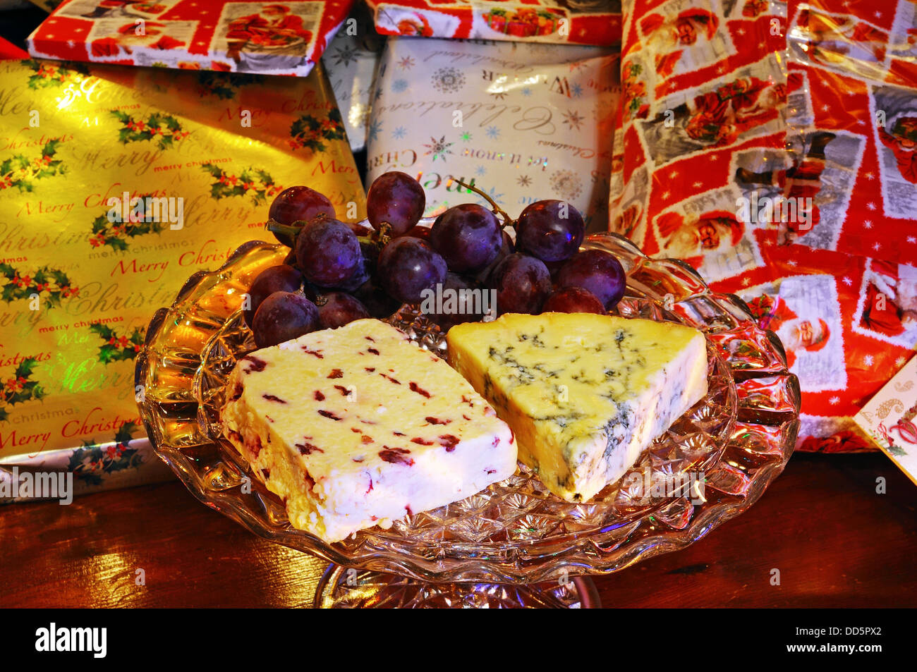 Wensleydale con mirtilli rossi e blu Stilton formaggi con uve rosse su una piastra di vetro stand con i regali di Natale alla parte posteriore Foto Stock