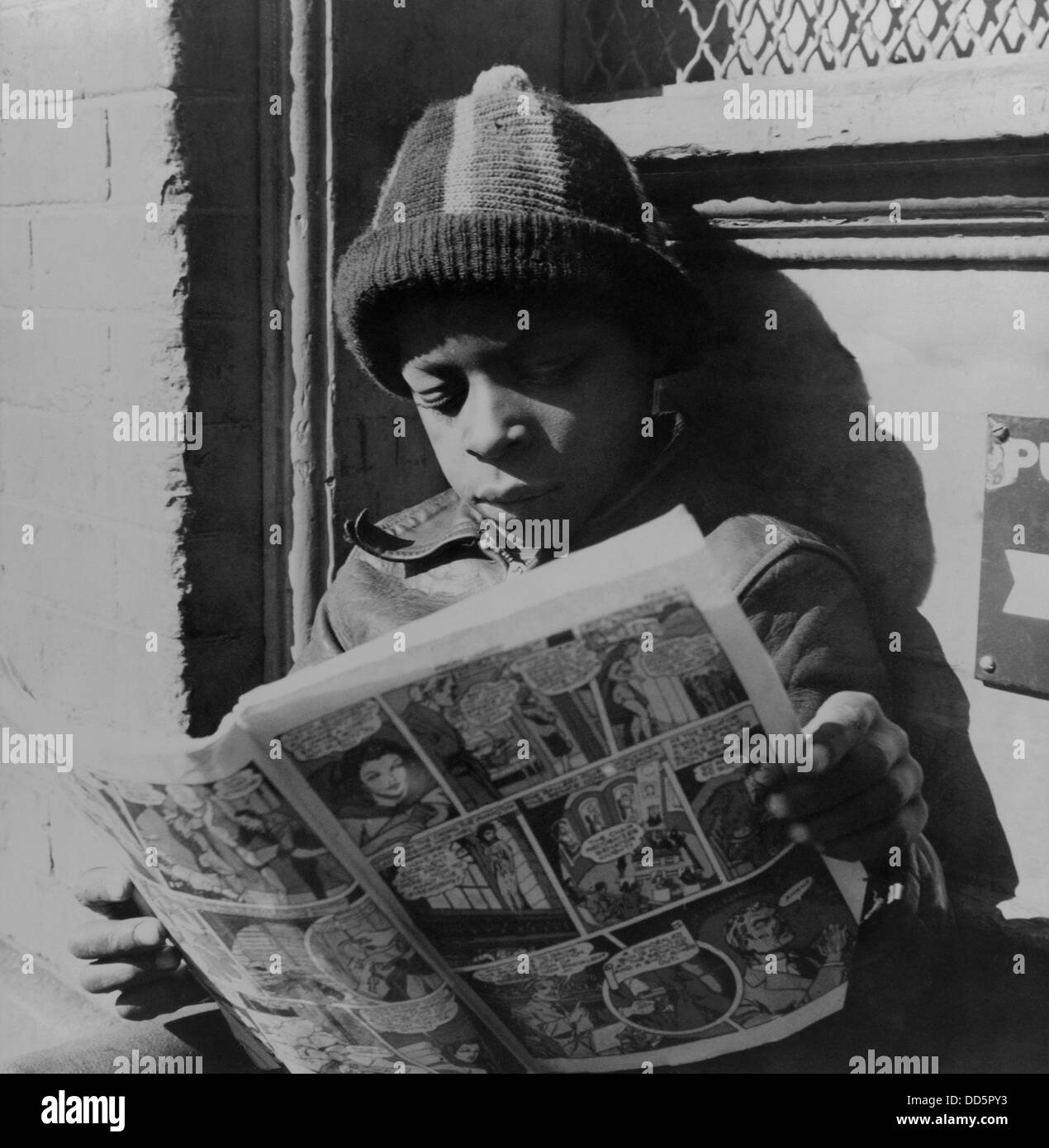 African American boy la lettura di un libro a fumetti, su un gradino della porta, nel sud-ovest della sezione, Washington D.C., nov. 1942. Foto di Foto Stock