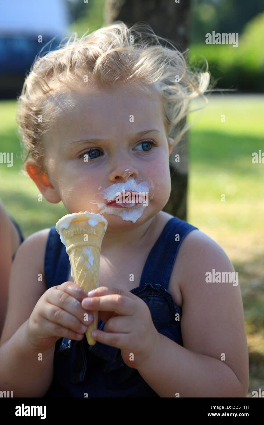 Due anno vecchia ragazza con gelato intorno alla bocca in una calda giornata estiva Foto Stock