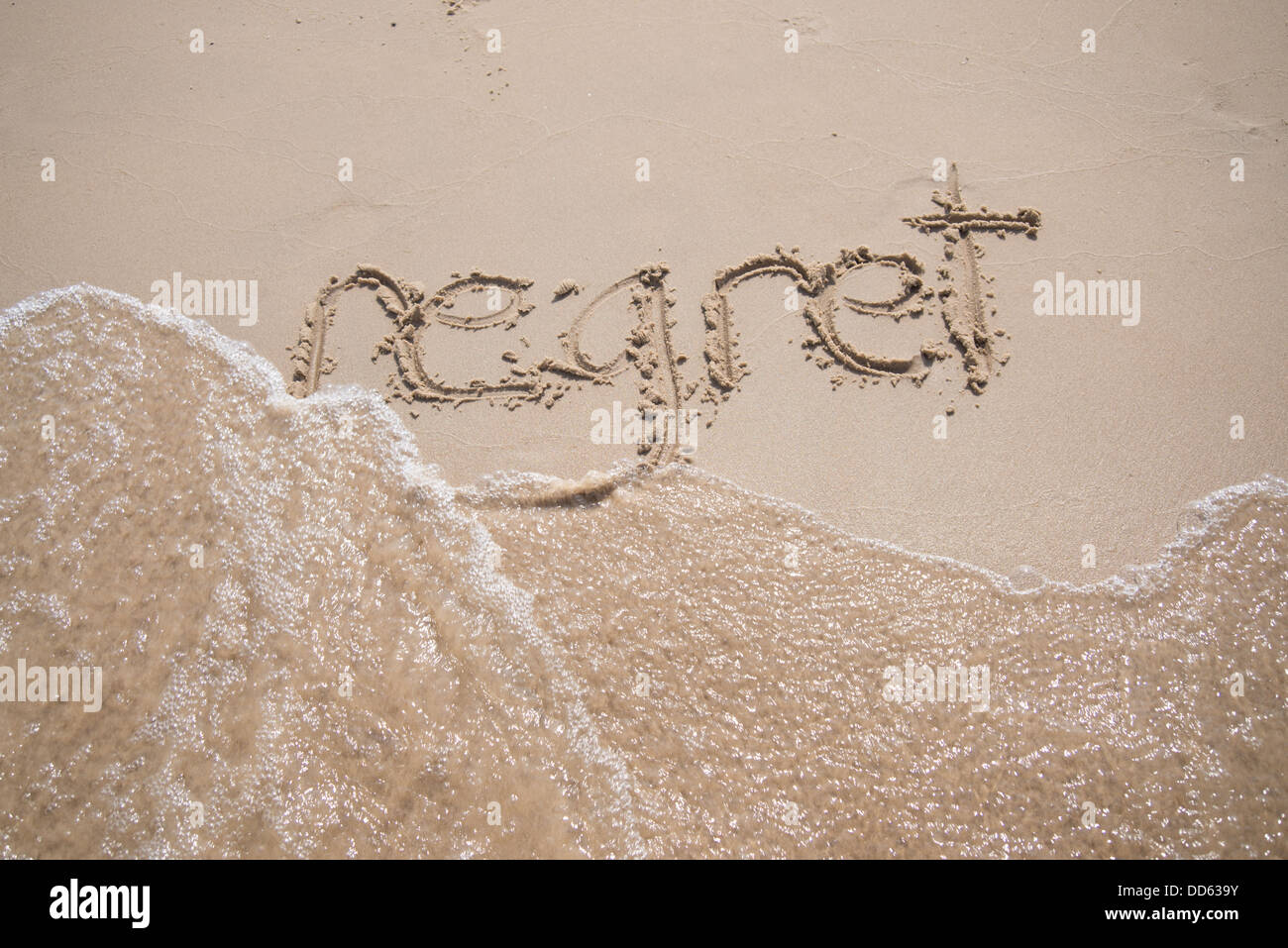 La parola "gret' scritto nella sabbia, essere lavato via da un'onda. Foto Stock