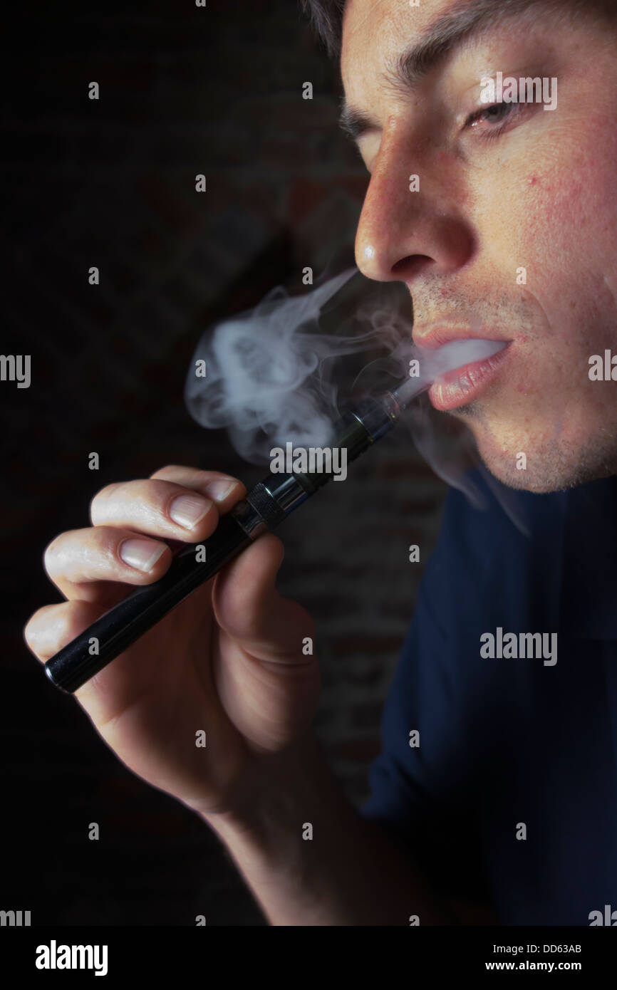 Respirazione maschio nel vapore da una sigaretta elettronica Foto Stock