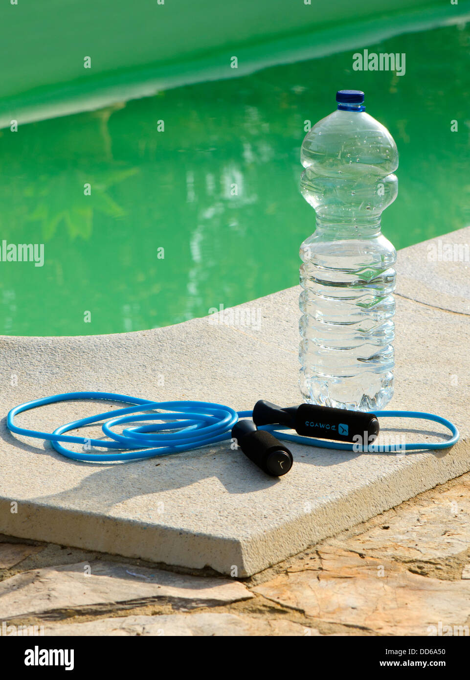 Corda da salto e una bottiglia di acqua vicino alla piscina Foto Stock