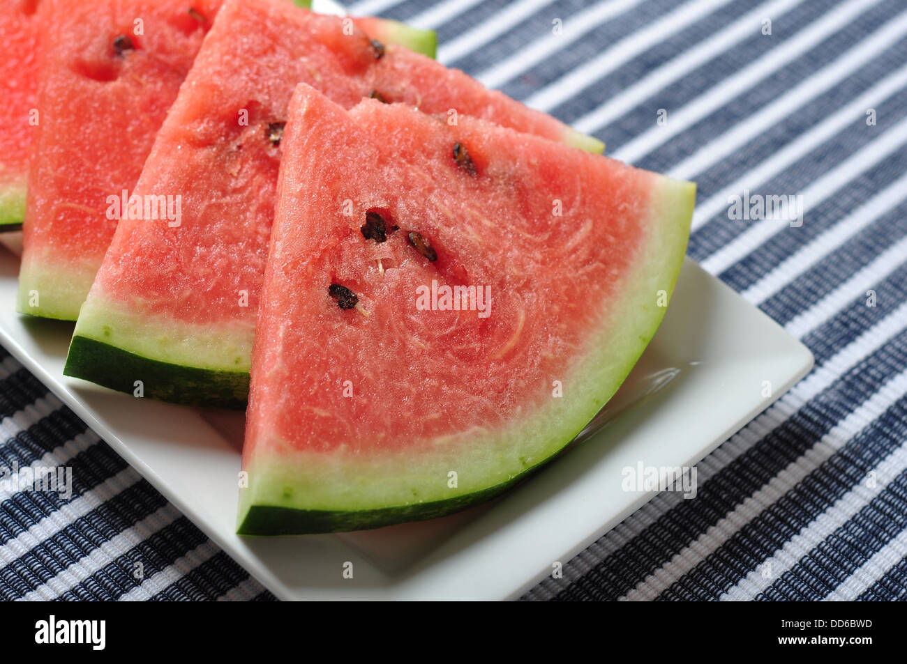 Tagliate a fette il melone di acqua su una piastra su sfondo blu Foto Stock