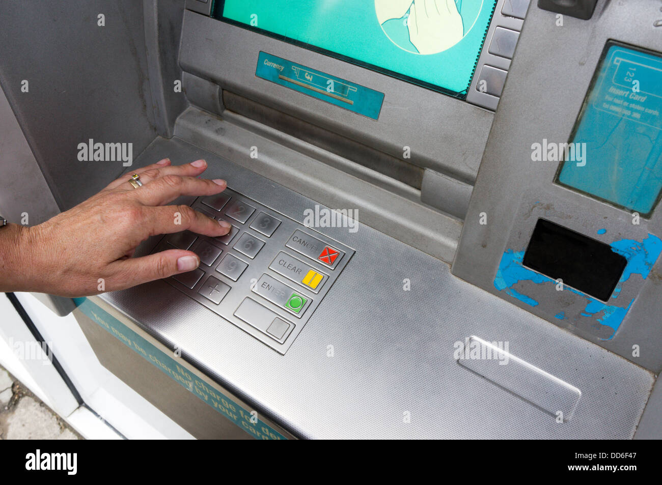 Una donna inserendo il suo numero PIN presso una banca bancomat. Foto Stock