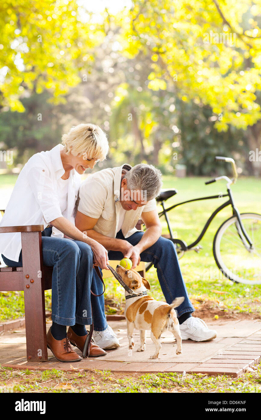 Felice Coppia di mezza età giocando con il loro cane al parco Foto Stock