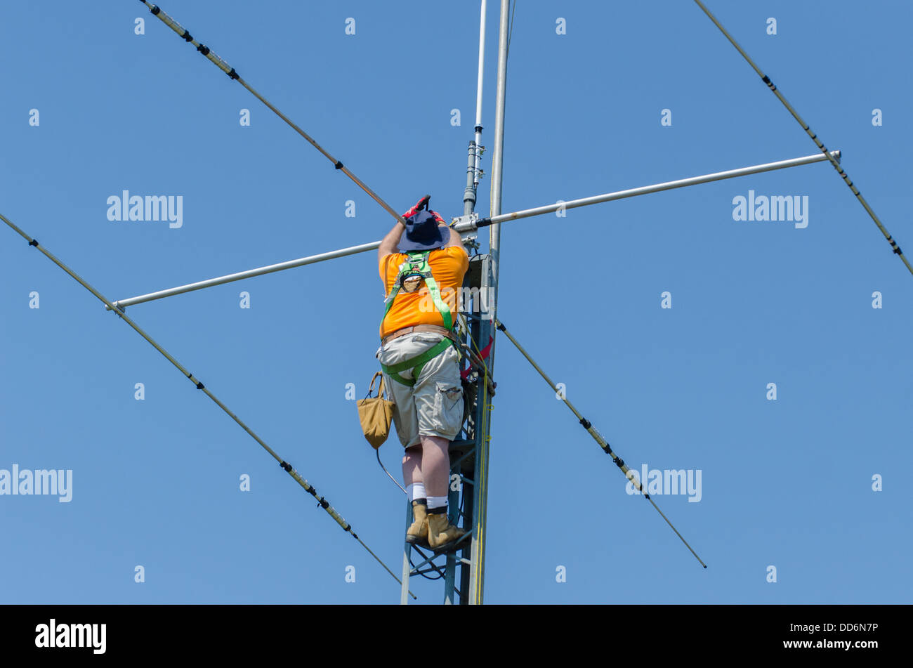 L uomo nel cablaggio di sicurezza installando un dilettante della torre radio e antenna. Foto Stock