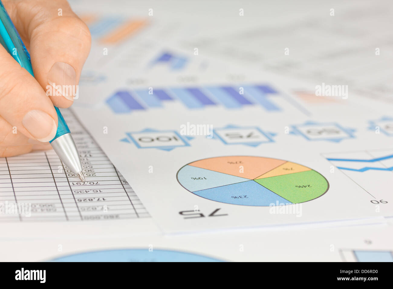 Mano con penna lavorando su fogli di calcolo e grafici Foto Stock