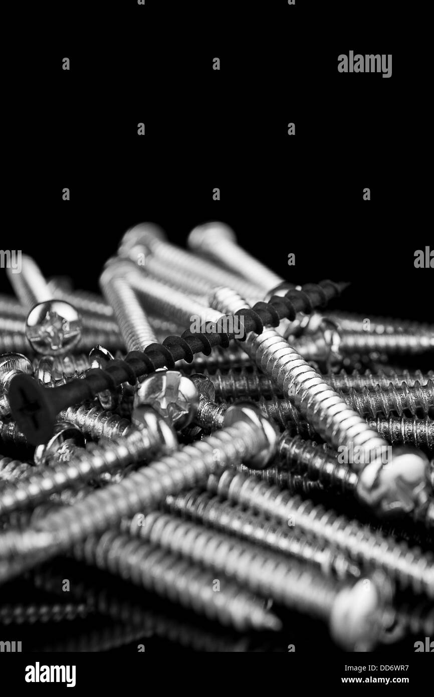 Macro, una vite nera in un mucchio di viti in ottone Foto Stock