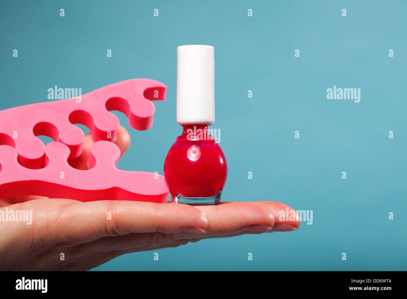 Pedicure accessori rosso smalto per unghie rosa e separatori di punta sul lato femmina sfondo blu Foto Stock