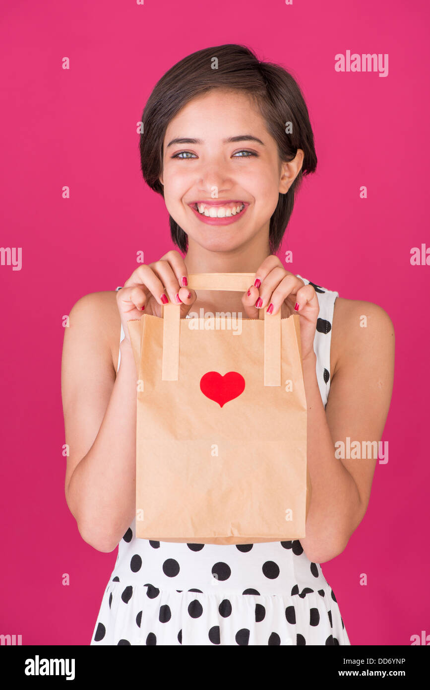 Giovane donna sorridente tenendo un il giorno di San Valentino shopping bag Foto Stock