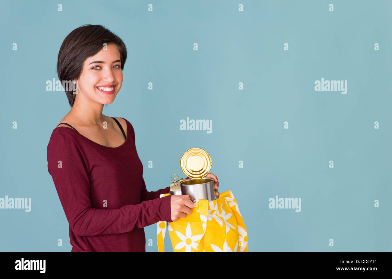 Ritratto di giovane sorridente multirazziale donna il riciclaggio di lattine di metallo Foto Stock