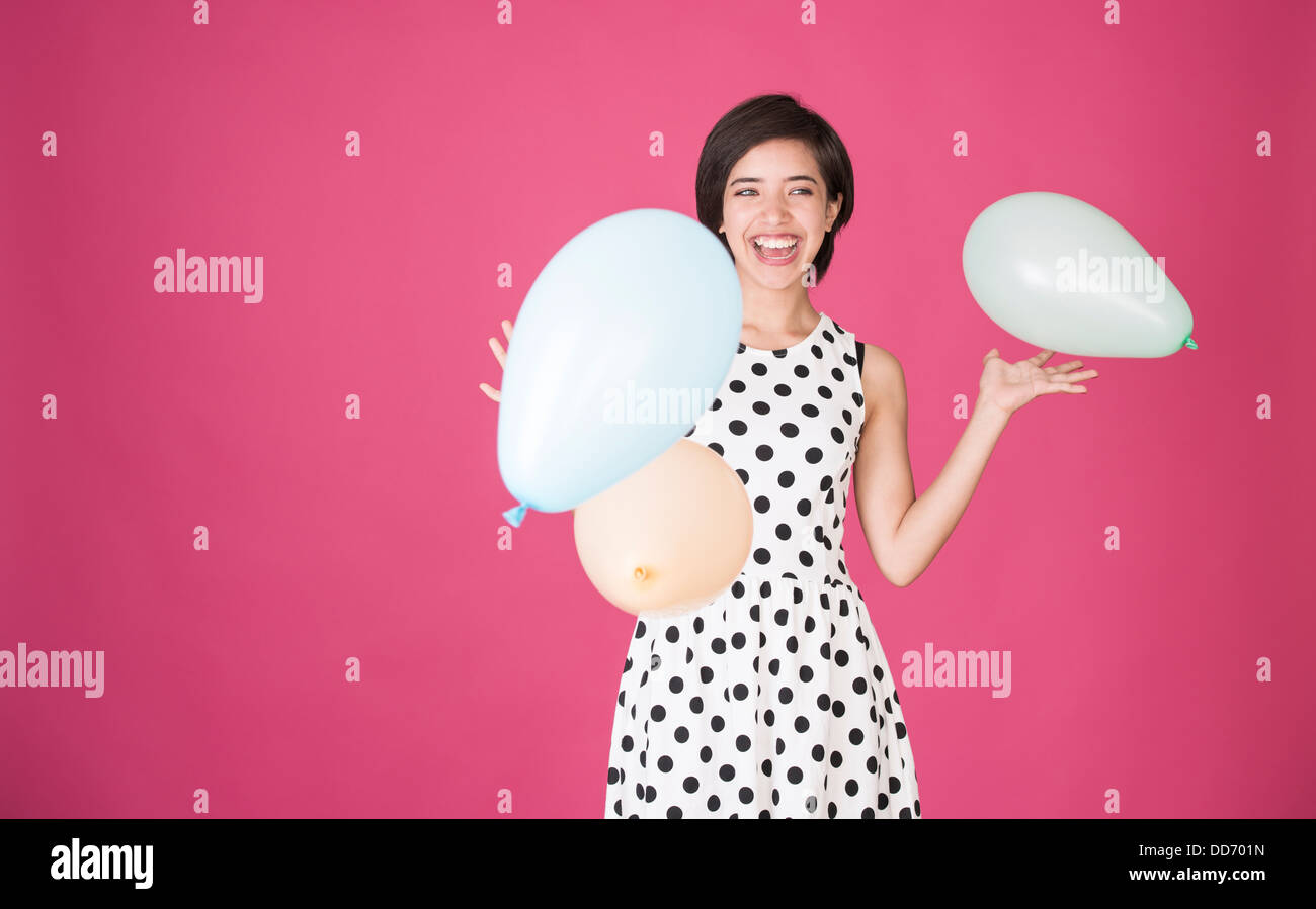 Giovane e bella donna multirazziale divertendosi con palloncini a celebrazione Foto Stock